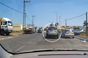 איור לשאלה: נתיב נסיעתך נחסם על ידי הרכב הכסוף החונה בחנייה כפולה (מסומן בעיגול). מה עליך לעשות?